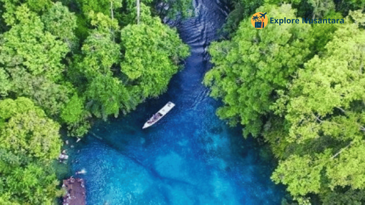 Air jernih di Danau Labuan Cermin dengan perahu mengambang di atas permukaan dua lapis